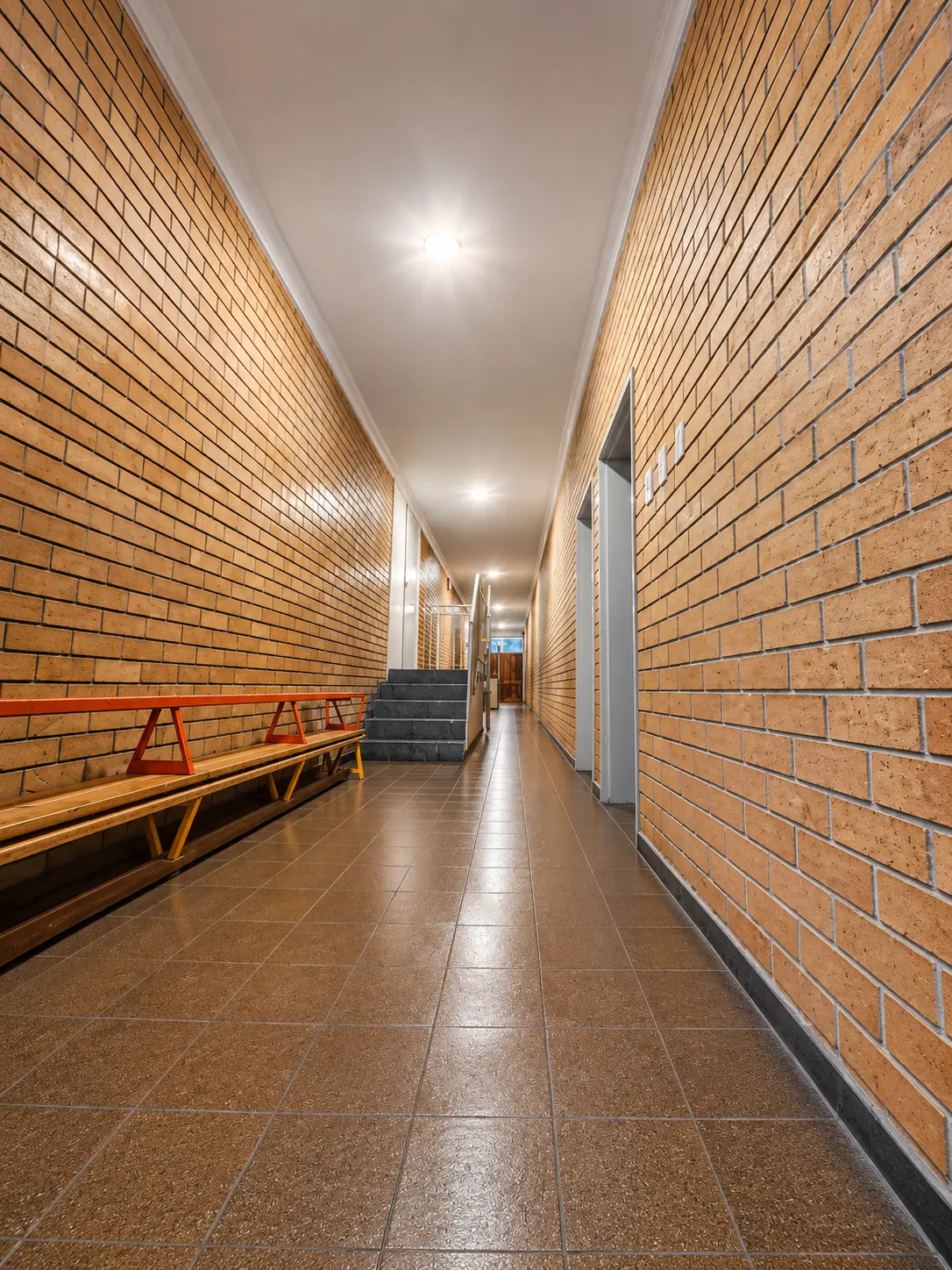Institutional corridor with face-brick walls and tiled floor